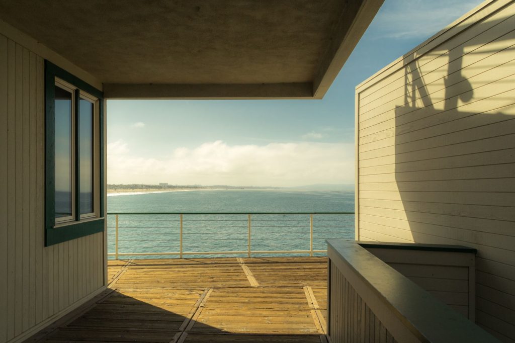 Wooden deck offering a calming ocean view framed by modern architecture under bright sunlight.